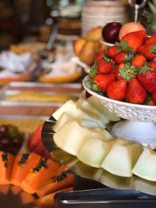 una mesa con una bandeja de fruta y un tazón de fresas en Pousada Castello Benvenutti, en Bento Gonçalves