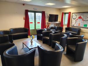a waiting room with leather chairs and a tv at FSC Preston Montford Hostel in Shrewsbury