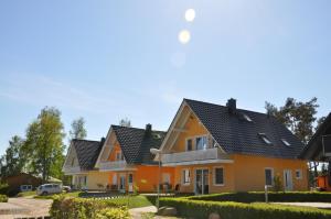 una fila de casas con techos negros en Ferienhaus Müritzbrise / EG-Appartement, en Marienfelde