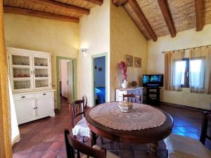 uma sala de jantar com uma mesa e cadeiras e uma televisão em Villa La Quercia - Capriccioli em Abbiadori