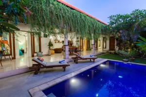 a swimming pool with two lounge chairs and a house at MasBro ART Villas in Seminyak