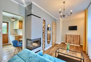 a living room with a blue couch and a fireplace at APARTAMENTY SPA & RESORT BUKOWIEC in Polańczyk