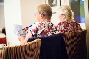 two older people sitting in a chair reading a book at Barrowfield Hotel in Newquay