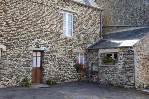 um edifício de tijolos com duas janelas e uma porta com flores em les Miquelots em Pont-d'Ouilly