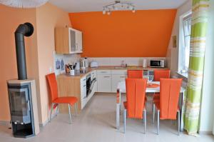 kuchnia z pomarańczowymi krzesłami, stołem i kuchenką w obiekcie Ferienhaus Müritzbrise / OG-Appartement w mieście Marienfelde