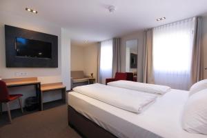 a hotel room with a bed and a desk and a television at City Hotel Würzburg in Würzburg