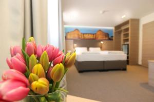 eine Vase mit Blumen auf einem Tisch in einem Schlafzimmer in der Unterkunft City Hotel Würzburg in Würzburg