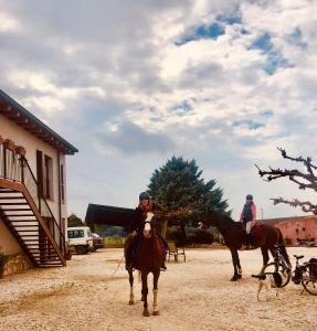 dos personas montando caballos en frente de un edificio en B&B El Ranxo, en Franciach