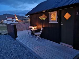 una terraza de madera con 2 sillas y una mesa. en Hjallurin, en Sandavágur