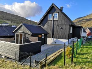 una casa negra con una escalera que conduce a ella en Hjallurin, en Sandavágur