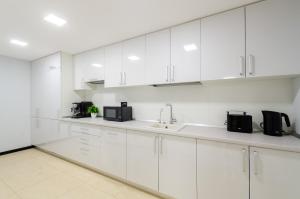 a white kitchen with white cabinets and a sink at Underground Hostel in Kyiv