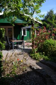 eine Terrasse mit einem Tisch und Stühlen vor einem grünen Haus in der Unterkunft Chalet t Kla-viertje in Klarenbeek