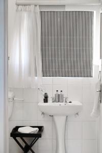 La salle de bains blanche est pourvue d'un lavabo et d'une douche. dans l'établissement The Lighthouse Guesthouse, à Colesberg