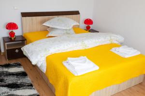 - une chambre avec 2 lits avec des draps jaunes et des lampes rouges dans l'établissement Pensiunea Aly, à Bumbesti Pitic