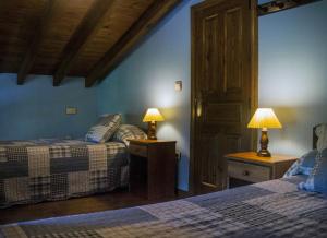 1 dormitorio con 2 camas y 2 lámparas en las mesas en La Casería de Los Hevia 1 y 2, en Arriondas