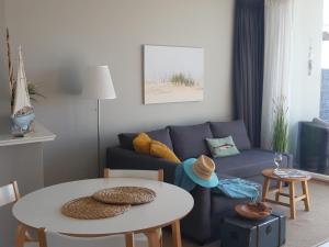 Una sala de estar con un sofá azul y una mesa. en Benny's Beach House 2, en Zandvoort