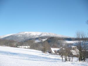 a snowy field with a house and a mountain at Ubytování u Janečků in Černý Dŭl