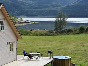 Eine Frau, die an einem Tisch auf einem Deck neben einem See sitzt. in der Unterkunft 7 person holiday home in Foldereid in Årfor