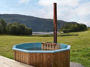 a wooden hot tub in a field with a pole at 7 person holiday home in Foldereid in Årfor
