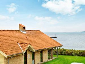 a house with an orange roof next to the ocean at 6 person holiday home in Egernsund in Egernsund