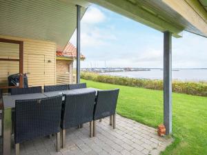 Egernsundにある6 person holiday home in Egernsundのパティオ(テーブル、椅子、水付)