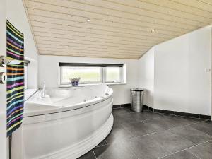 uma grande banheira branca numa casa de banho com uma janela em Holiday home Hadsund XLIX em Sønder Hurup