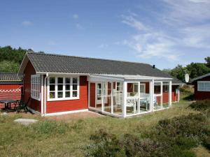een rood huis met een veranda en een tafel bij 6 person holiday home in lb k in Ålbæk