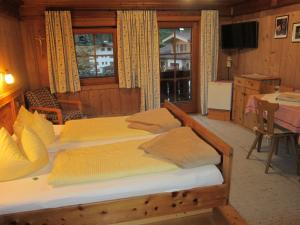 a bedroom with two beds and a table and a television at Hansenhof in Prägraten
