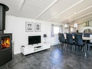 a living room with a fireplace and a table with chairs at 8 person holiday home in Vejers Strand in Vejers Strand