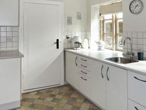kuchnia z białymi szafkami, umywalką i oknem w obiekcie 4 person holiday home in Aabenraa w mieście Kværs