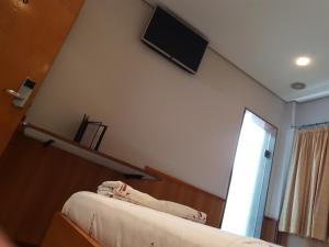 a bedroom with a bed and a tv on the wall at Hotel Três Poderes in São Paulo