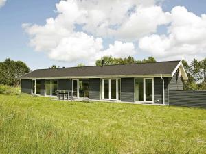 a gray house with a large grass field at Four-Bedroom Holiday home in Ålbæk 4 in Ålbæk