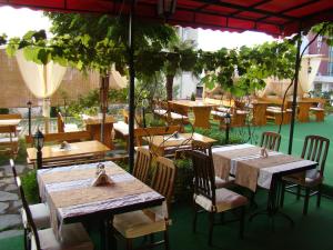 a restaurant with wooden tables and chairs under an umbrella at Hotel Bellisimo in Lozenets