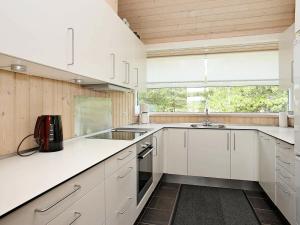 uma cozinha com armários brancos, um lavatório e uma janela em Three-Bedroom Holiday home in Jerup 8 em Jerup
