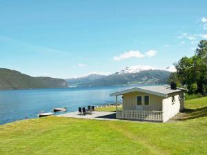 a house on the shore of a lake with mountains at Two-Bedroom Holiday home in Utvik 3 in Reed