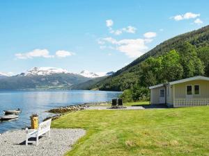 a house with a bench next to a lake at Two-Bedroom Holiday home in Utvik 3 in Reed