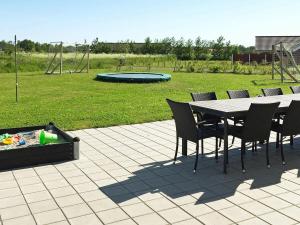 a patio with a table and chairs and a playground at 14 person holiday home in Idestrup in Marielyst