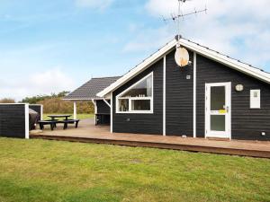 a black house with a deck and a picnic table at 8 person holiday home in Harbo re in Harboør