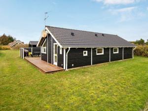 a black house with a wooden deck in a field at 8 person holiday home in Harbo re in Harboør