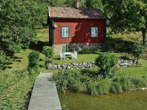 una casa rossa con una passerella in legno che conduce a un fiume di 5 person holiday home in MARIEFRED a Mariefred