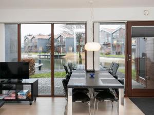 ボーゲンセにあるTwo-Bedroom Holiday home in Bogense 7のダイニングルーム(テーブル、椅子付)、大きな窓が備わります。