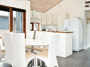 Thorsmindeにある8 person holiday home in Ulfborgのキッチン(白い椅子、テーブル、冷蔵庫付)