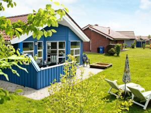 ein blaues Haus mit einem Garten mit Stühlen in der Unterkunft 6 person holiday home in Otterndorf in Otterndorf