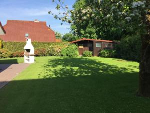 a yard with a green lawn with a house at Ferienhaus Sonnenschein Heyken in Werdum