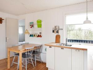 a kitchen with white cabinets and a wooden table at Lovely Holiday Home with Terrace in Vejers Strand in Vejers Strand