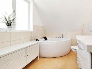 ein weißes Badezimmer mit einer Badewanne und einem Waschbecken in der Unterkunft 6 person holiday home in Wendtorf in Wendtorf