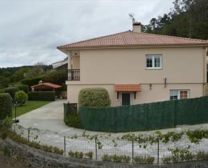 una casa blanca con una valla delante en Casa Playa de Rostro, en Finisterre