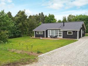 een klein zwart huis met een grote tuin bij Three-Bedroom Holiday home in Løgstør 6 in Trend