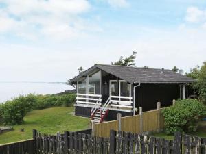 a small black house with a wooden fence at 7 person holiday home in Struer in Remmer Strand