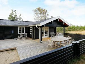 une maison dotée d'une terrasse en bois avec une table et des chaises dans l'établissement 6 person holiday home in lb k, à Ålbæk